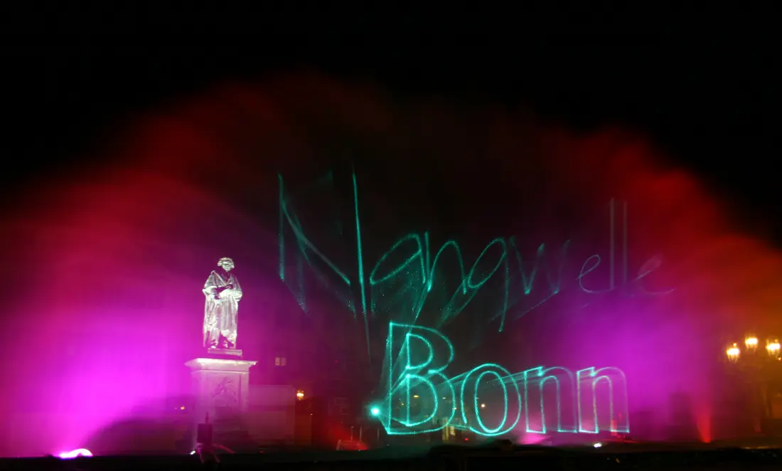Lasershow mit Schriftzug vor historischem Denkmal in der Stadt
