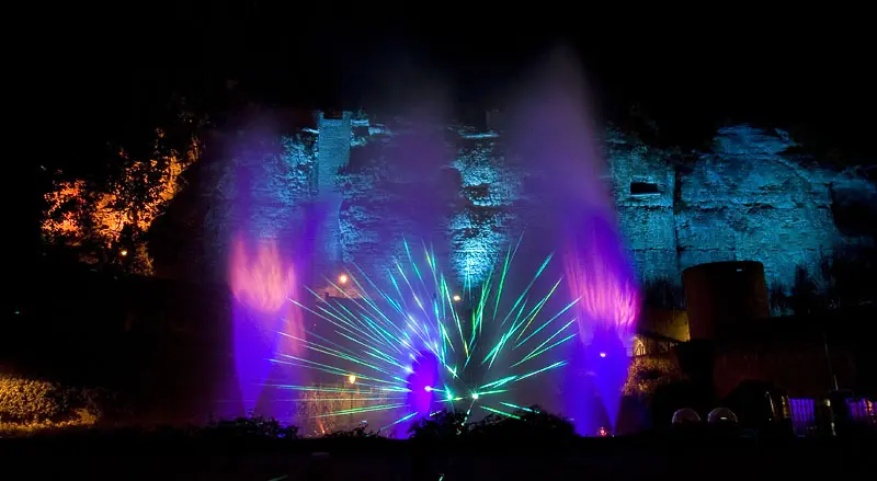Fontänen und Laserfächer vor beleuchteter Burgmauer