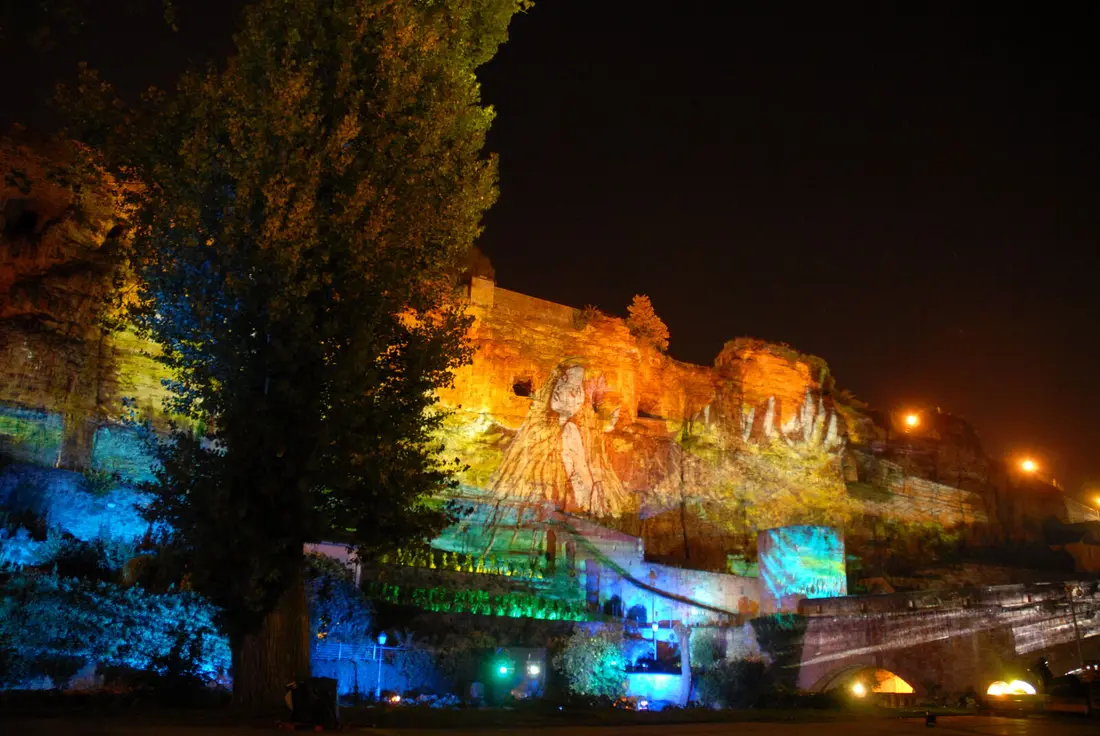 Projection Mapping auf historischer Festungsmauer, mehrfarbige Lichtinstallation bei Nacht