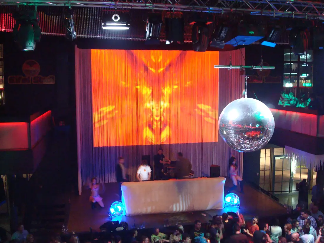 Discokugel und Projektionswand in belebtem Club