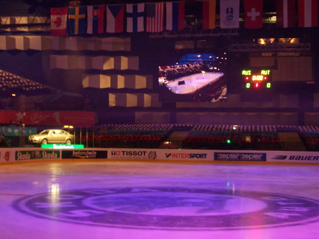 Eishockey-Arena mit Nationenflaggen und Anzeigetafel